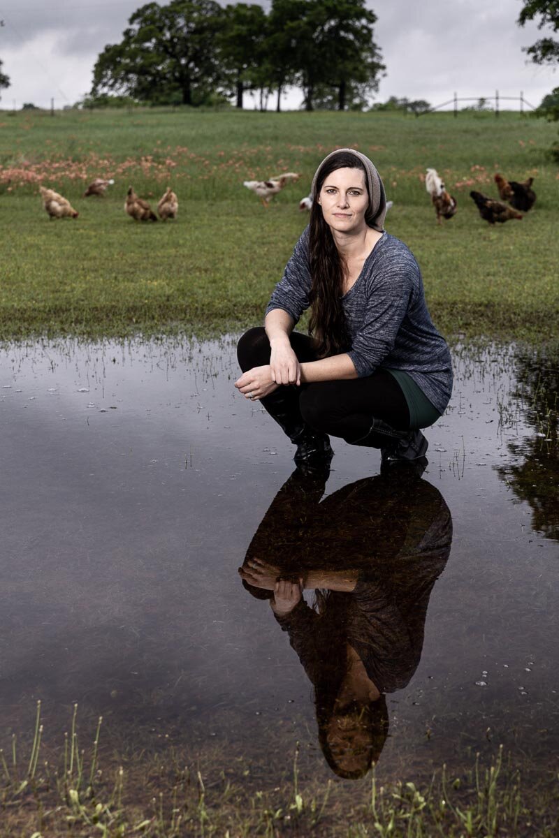 Kate Matthews crouched in a pasture among free-range chickens