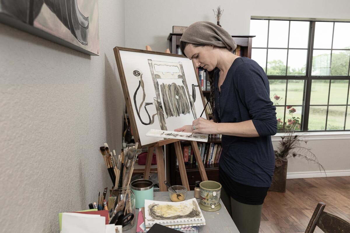 Kate Matthews painting at her easel in her home studio